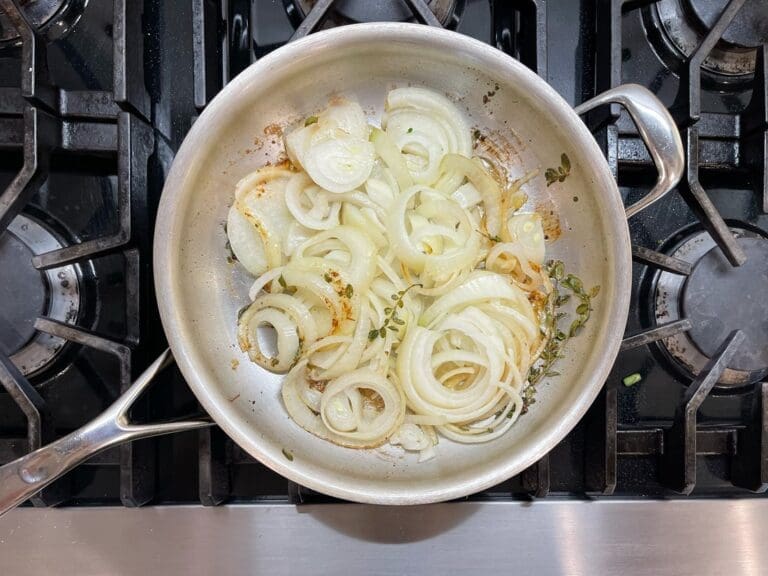 Image of Demeyere's Stainless Steel Atlantis fry pan with pan carmelized onions, thyme and marjoram in olive oil. It's beautiful premium clean  cookware. This stainless steel cookware set is a favorite of mine, Laura Klein.