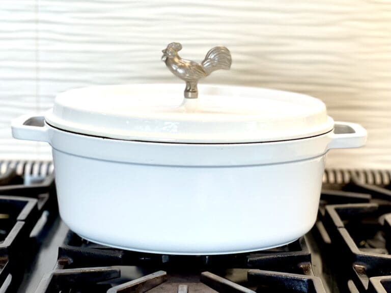 Laura Klein's Staub white oval cocotte on gas stove top makes naturally non stick cooking a breeze. Staub's Dutch Ovens are free of toxic metals and have a textured surface and is metal utensil safe that is excellent for searing. It is an excellent piece of cookware.