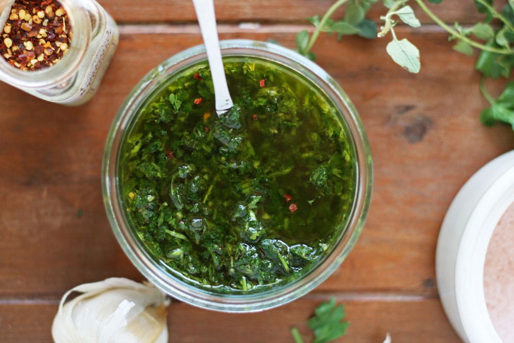 Image of chimichurri in a bowl from overhead that goes well on marinated grilled chicken kabobs with vegetables