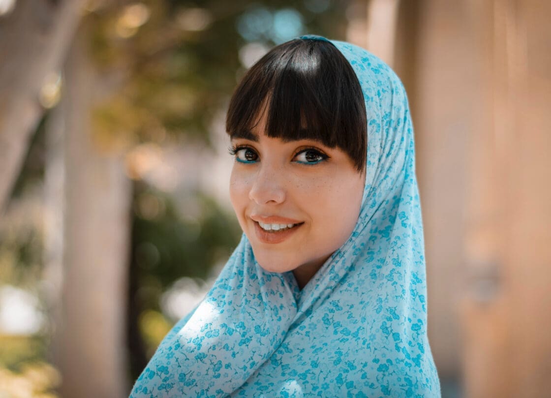 young woman in blue floral hijab with matching blue eyeliner showing smooth skin from collagen powder supplement use that may help with aging, wrinkles and sagging skin via Organic Authority