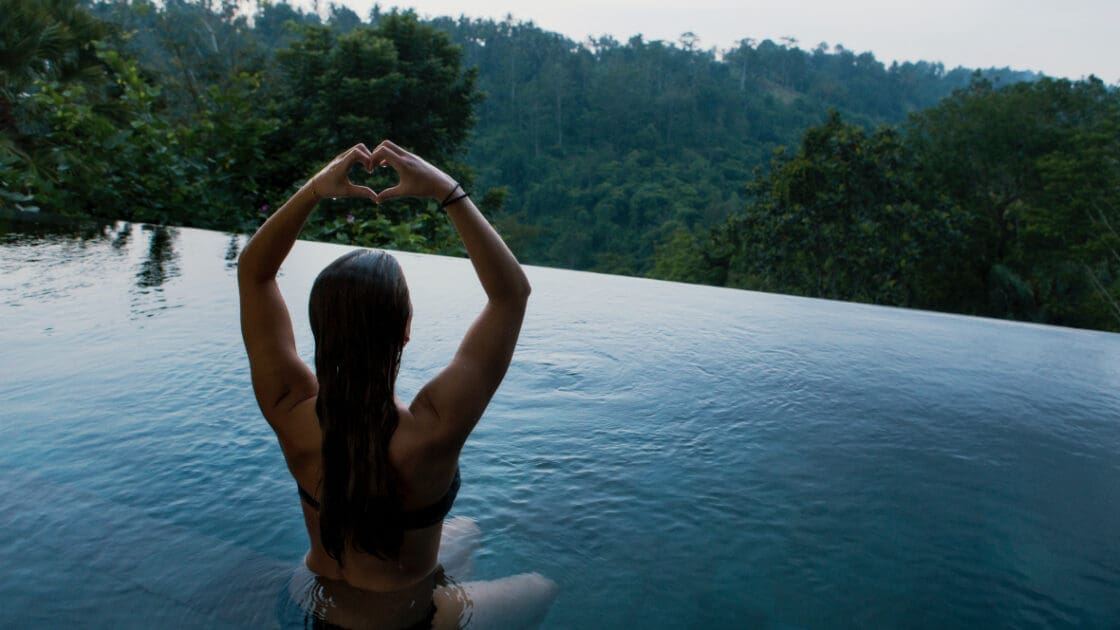 Kirtan quiets the mind and opens the heart. Image of Woman sitting in infinity pool looking over Ubud.