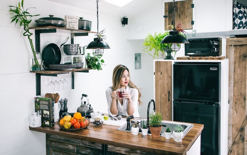young asias woman in her kitchen sipping tea