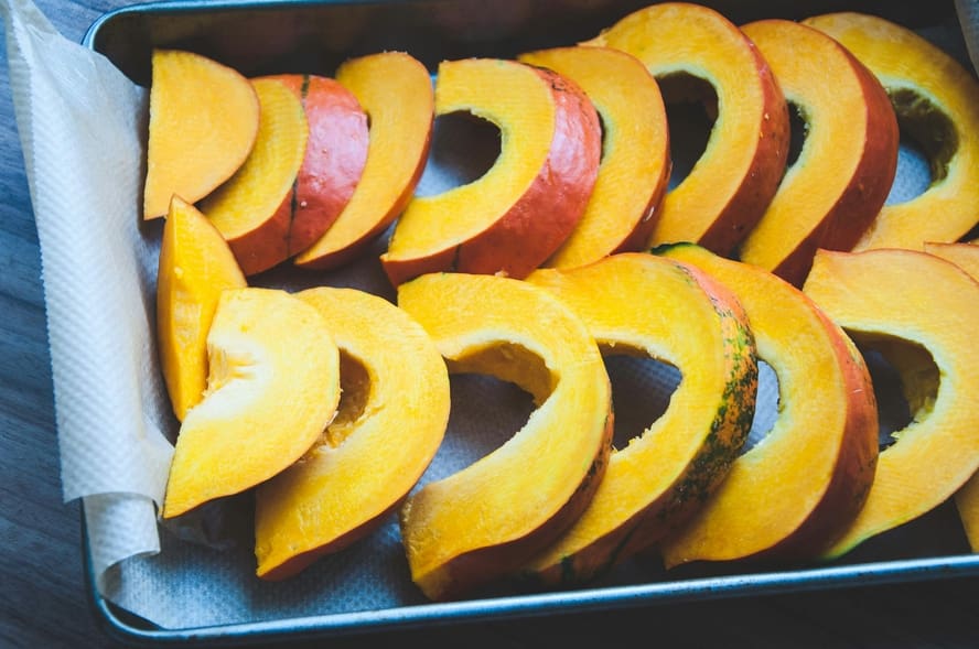Image of sliced heirloom pumpkin on a baking tray with parchment paper, ready to be roasted.