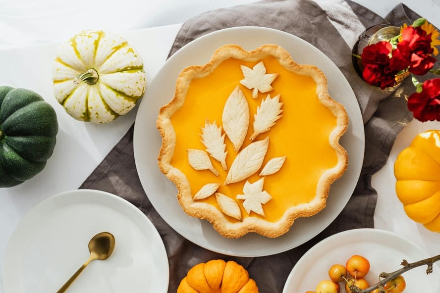 Image of a plate with pumpkin pie on a beautifully arranged fall table, including a couple of heirloom pumpkins.