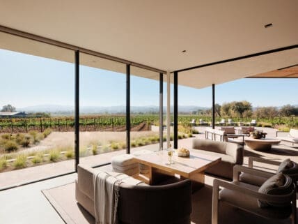 Image of the wine tasting room in Aperture Cellars, with a table and plush seating overlooking an expansive view of the vineyard.