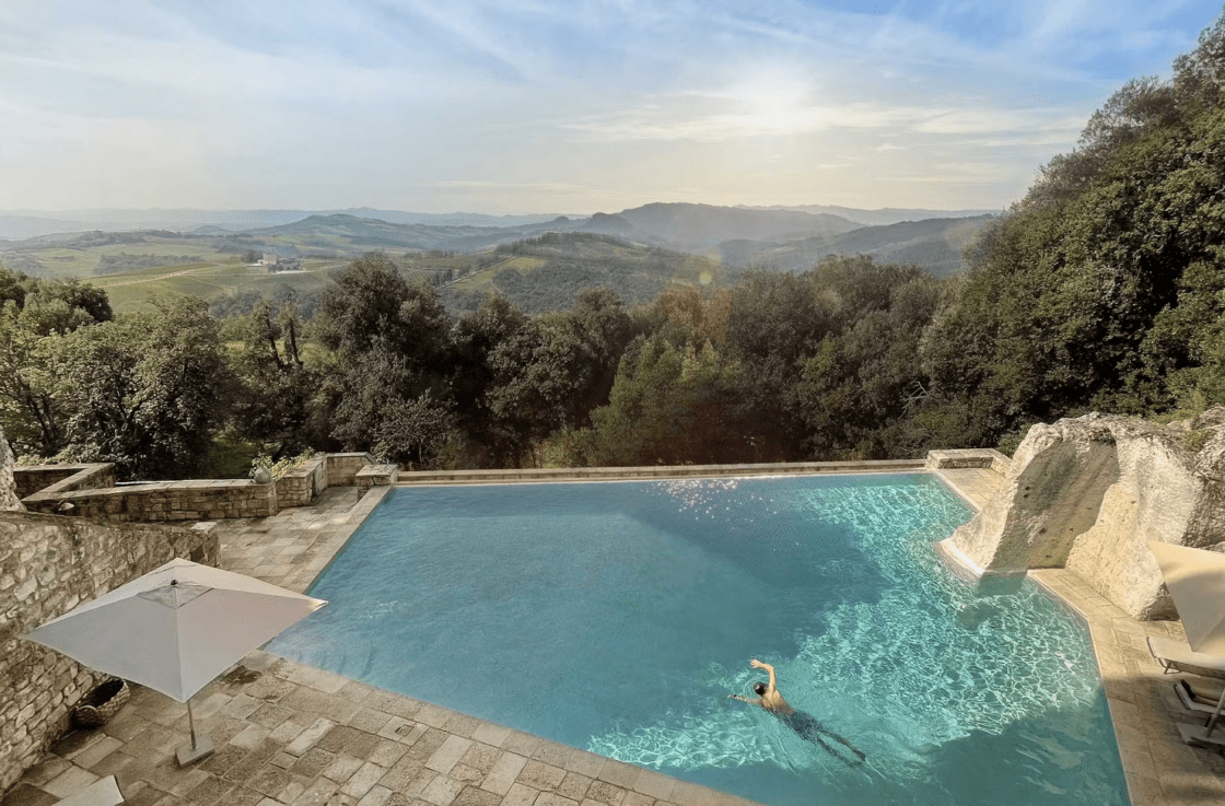 Image of saltwater infinity pool at the Tuscan villa Borgo Pignano, a green luxury hotel with views of the Tuscan woods.