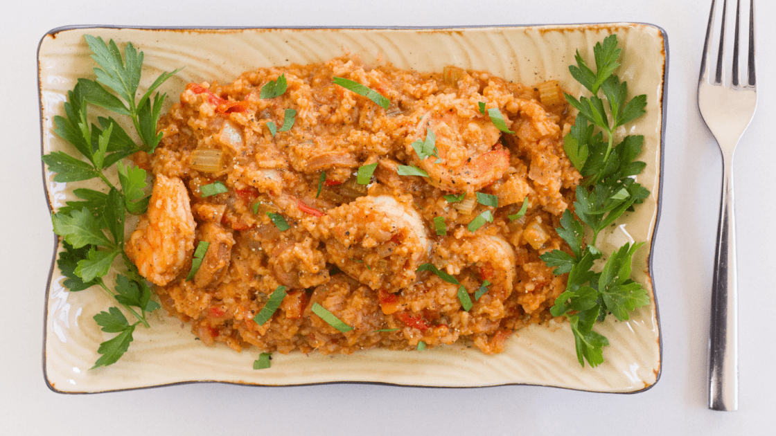 Image of a rectagular plate piled high with a jambalaya recipe with shrimp, andoille sausage, and chicken. But this version can easily be made vegetarian, too!