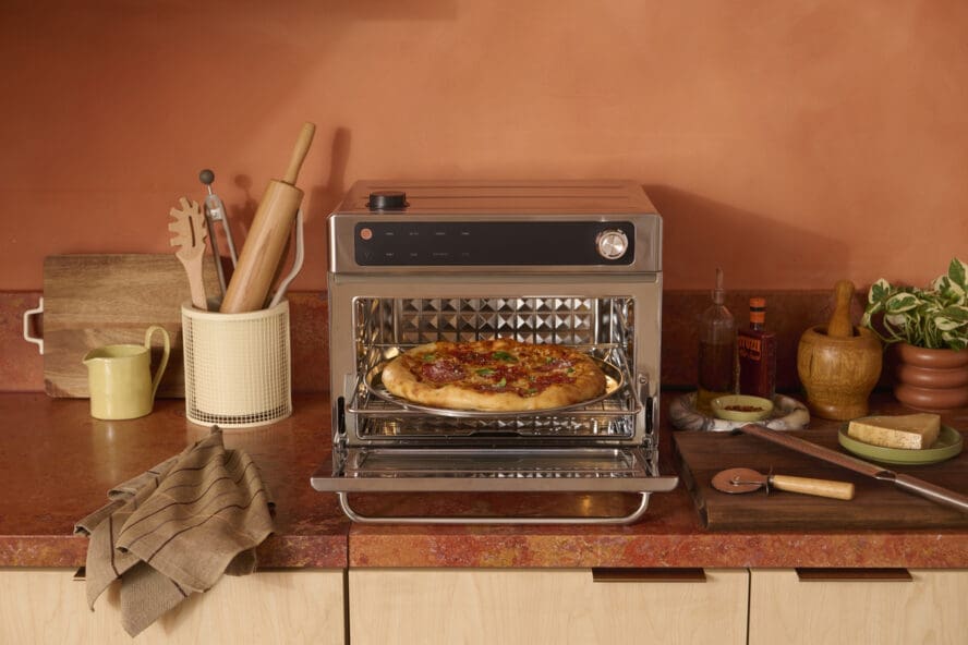 Image of the Our Place Wonder Oven Pro in stainless steel being used to bake a sopressata pizza.