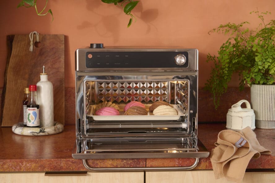 Image of the Our Place Wonder Oven Pro in stainless steel being used to bake conchas in a terracotta kitchen.