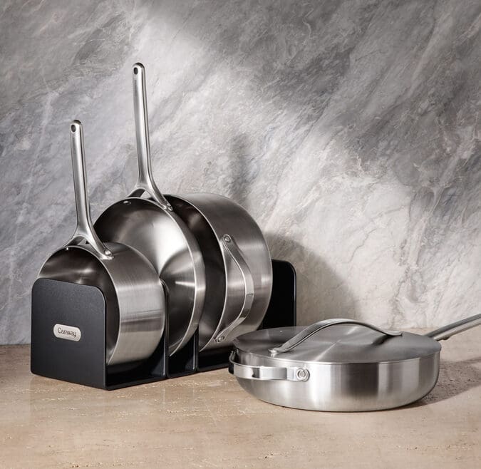 Image of several pieces in the Caraway Stainless Steel collection, including the storage system that comes with the set.