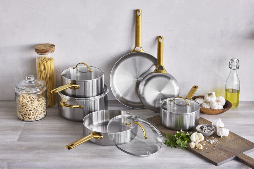 Image of the GreenPan Reserve Stainless Steel 10-piece set with eye-catching gold handles, laid out across a countertop with ingredients.
