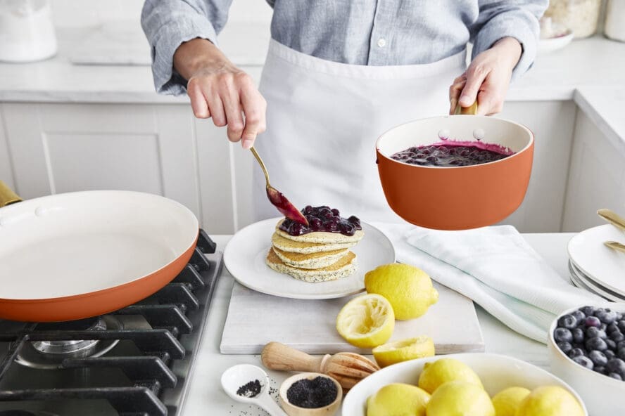 Image of a GreenPan Reserve Pro saucepan filled with blueberry compote being spooned over a stack of pancakes.