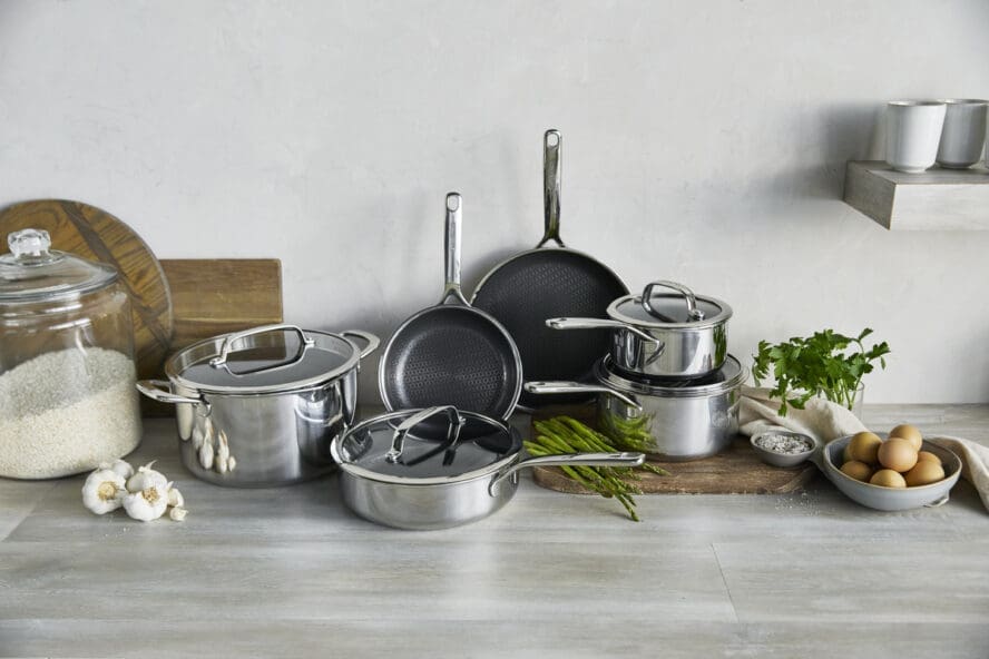 Image of the GreenPan Spectra 11-piece set displayed on a big countertop in a kitchen alongside ingredients like eggs, asparagus, cilantro, and more.