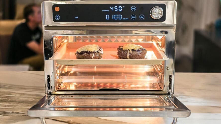 Image of two burger patties in the Our Place Wonder Oven Pro, with gooey melted cheese broiling on top.