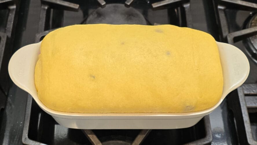 Image of a proofed loaf of brioche rising in an Our Place loaf pan on a stovetop.