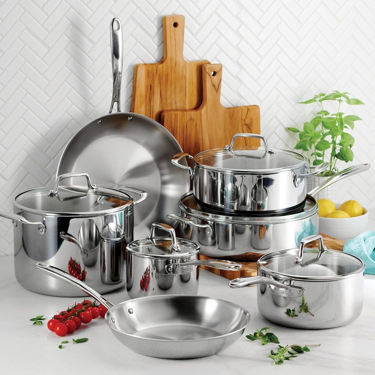 Image of a Tramontina 12-piece stainless steel cookware set, all stacked and displayed in a gorgeous white kitchen.