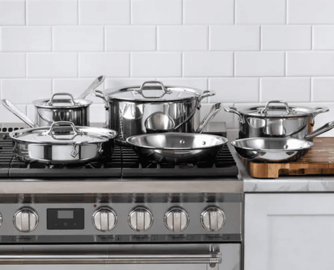 Image of the All-Clad D3 10-piece Stainless Steel set displayed on a gas stovetop in a brightly lit kitchen.