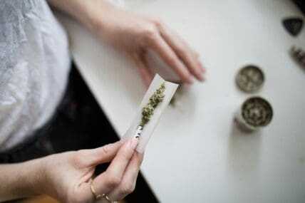 Image of a pair of hands rolling a cannabis joint over a counter.